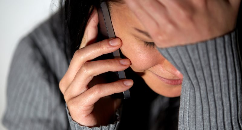 people, helpline and domestic violence concept - close up of unhappy woman crying and calling on smartphone